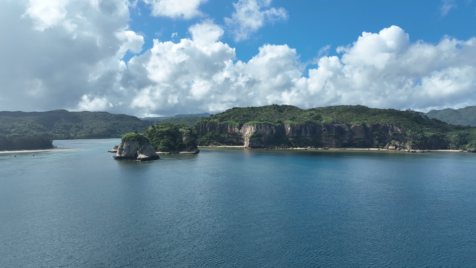 藍色水域和雲朵環繞的綠色島嶼的美麗景觀