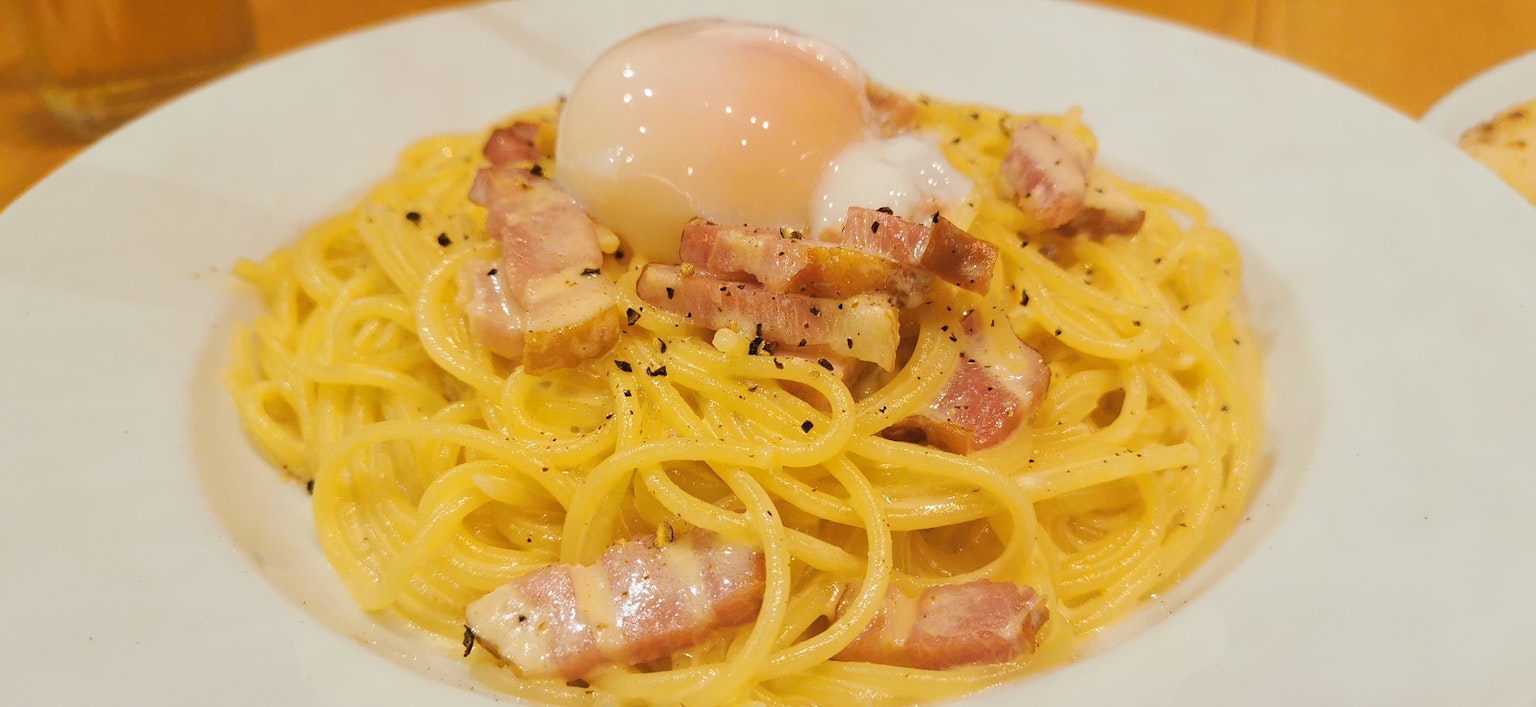 Cremige Carbonara-Pasta mit einem weichgekochten Ei und Speck