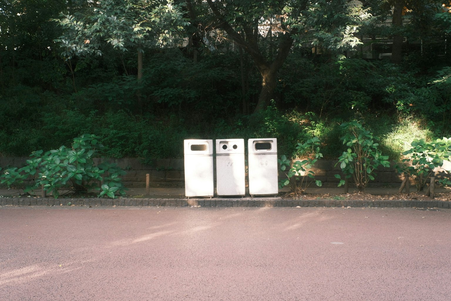 公園の近くにある三つのゴミ箱 緑の木々に囲まれた静かな環境