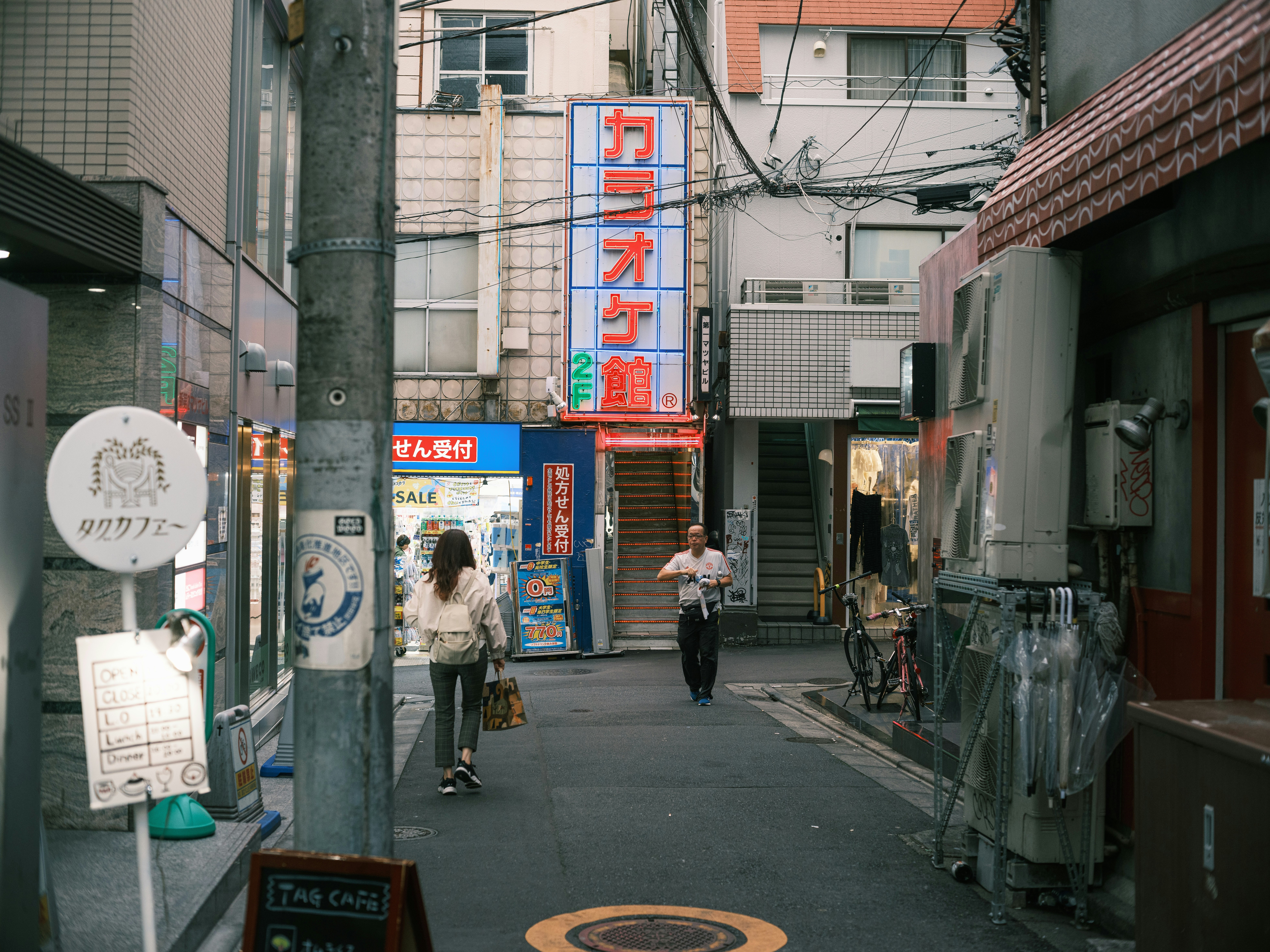 路地に並ぶ看板と人のいる商店街の通り
