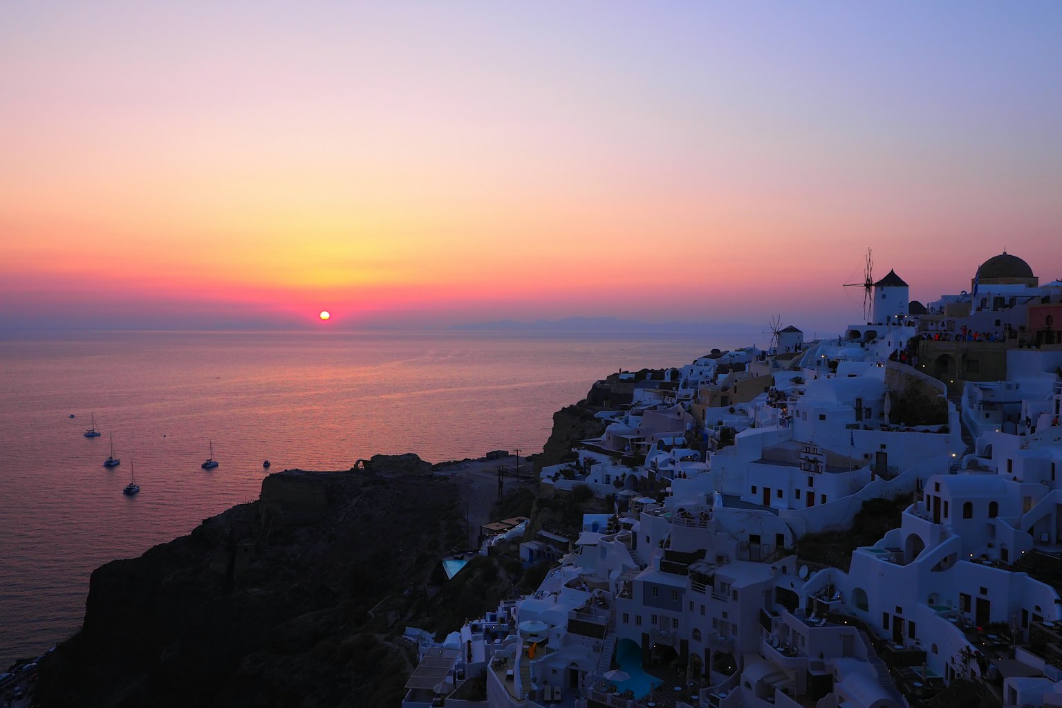 Sonnenuntergang in Santorin mit weißen Gebäuden über dem Meer