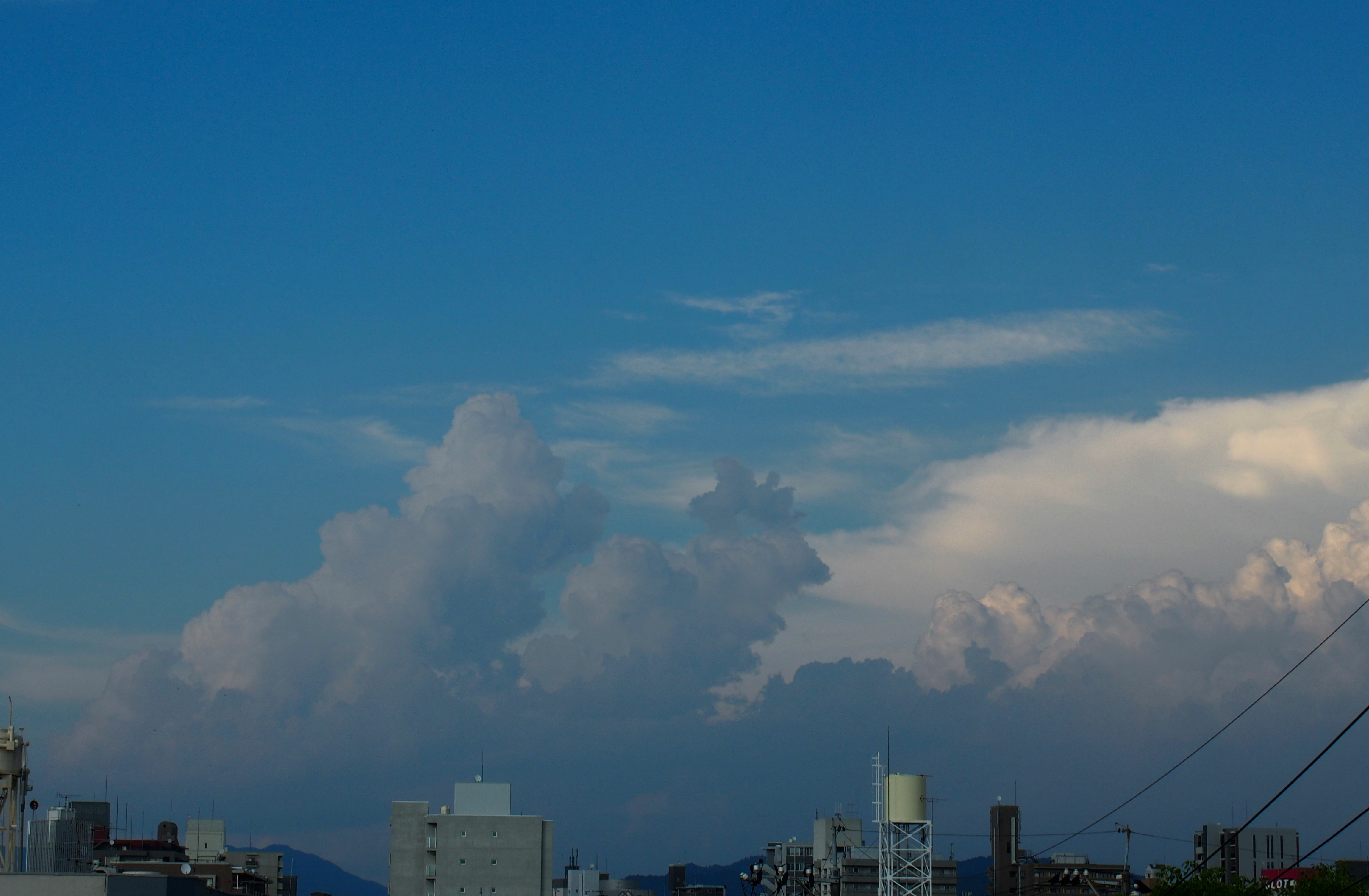 工場の煙突から立ち上る煙と青空の空模様