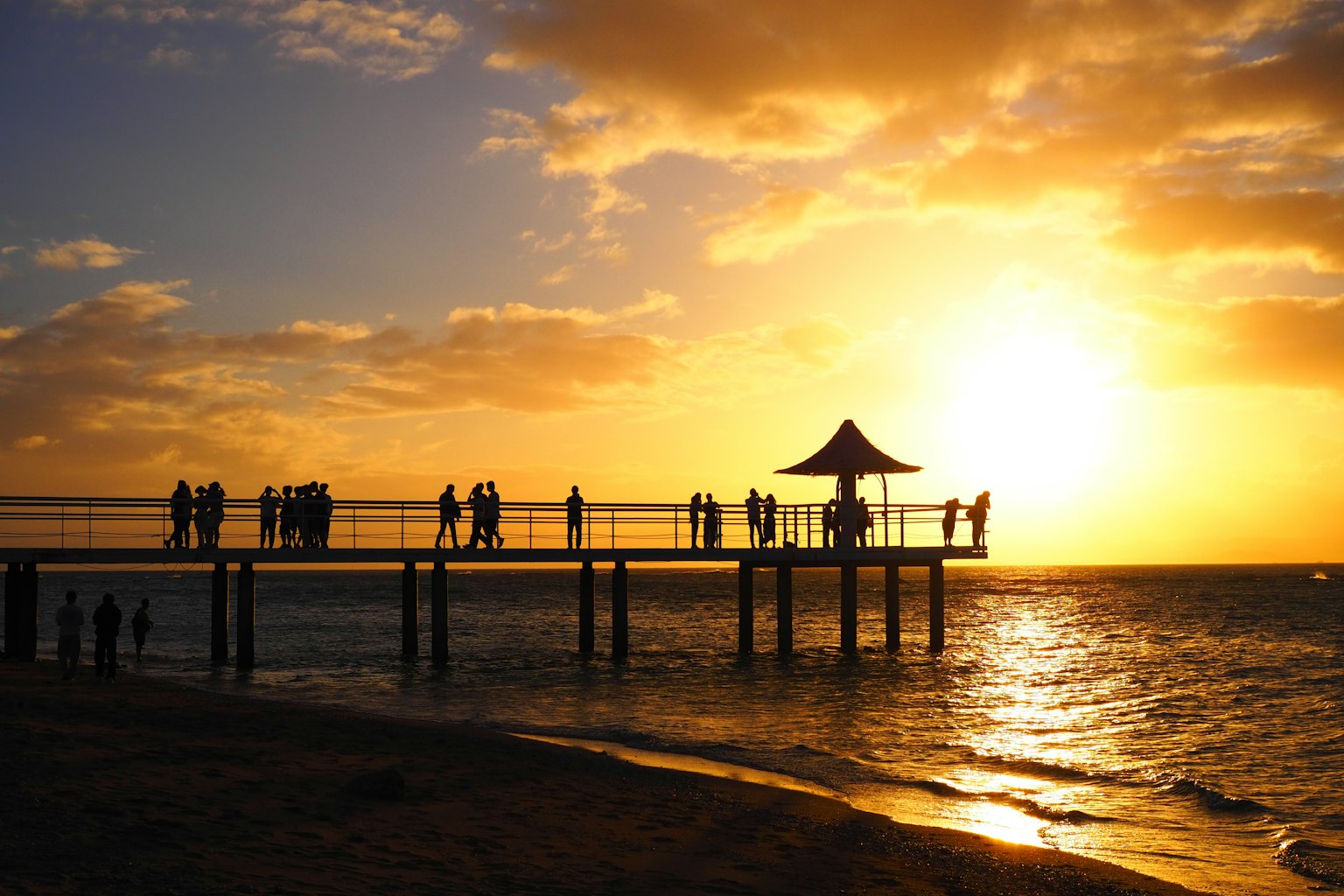 Silueta de personas en un muelle durante el atardecer