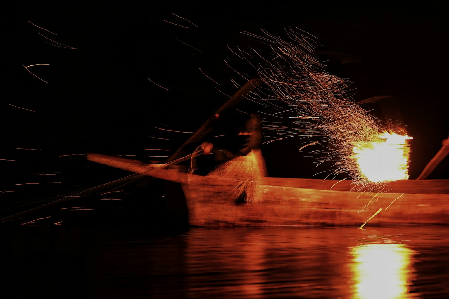 Bote de madera en el agua de noche con chispas