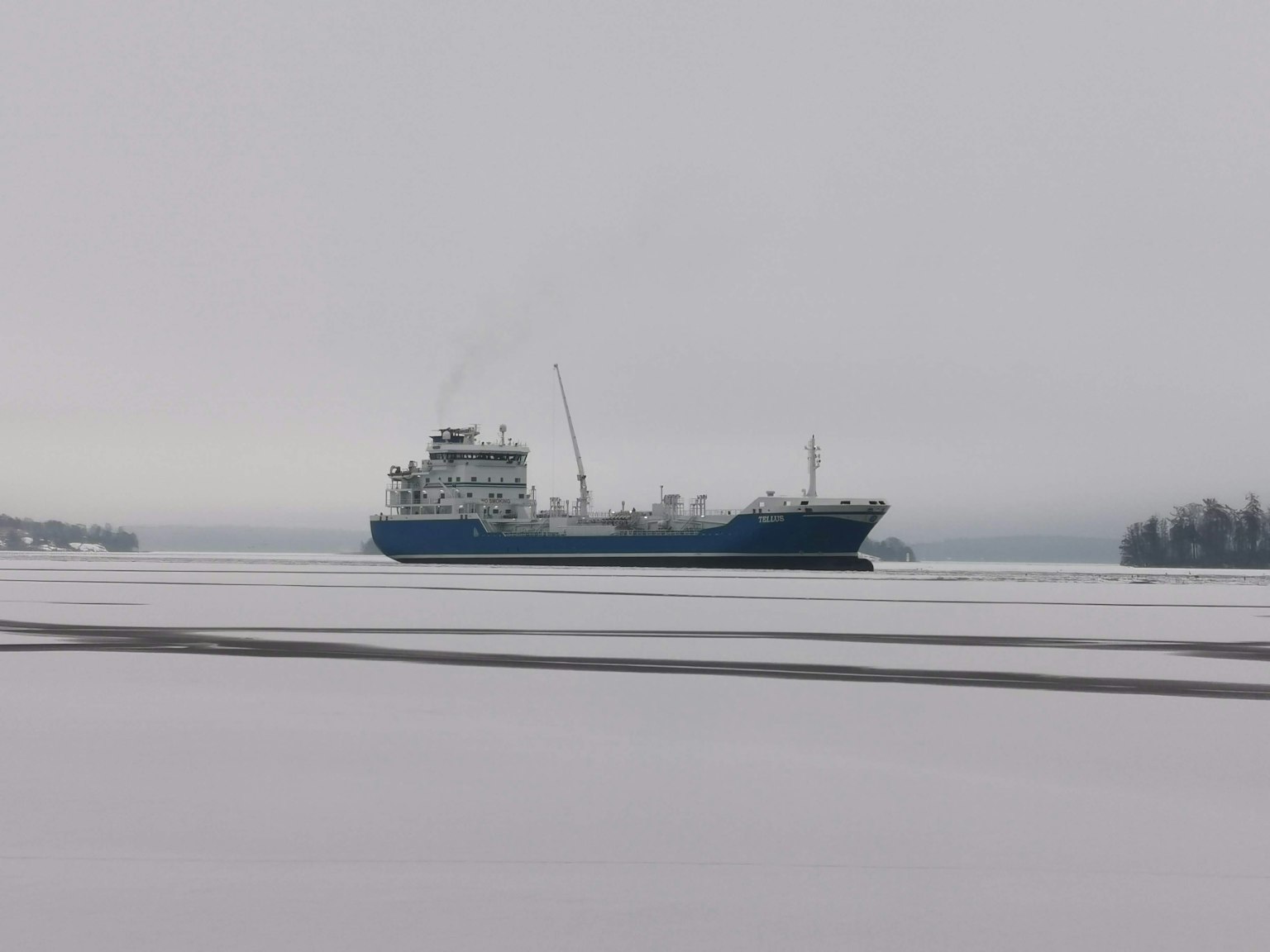 Un cargo bleu naviguant sur des eaux glacées dans le brouillard
