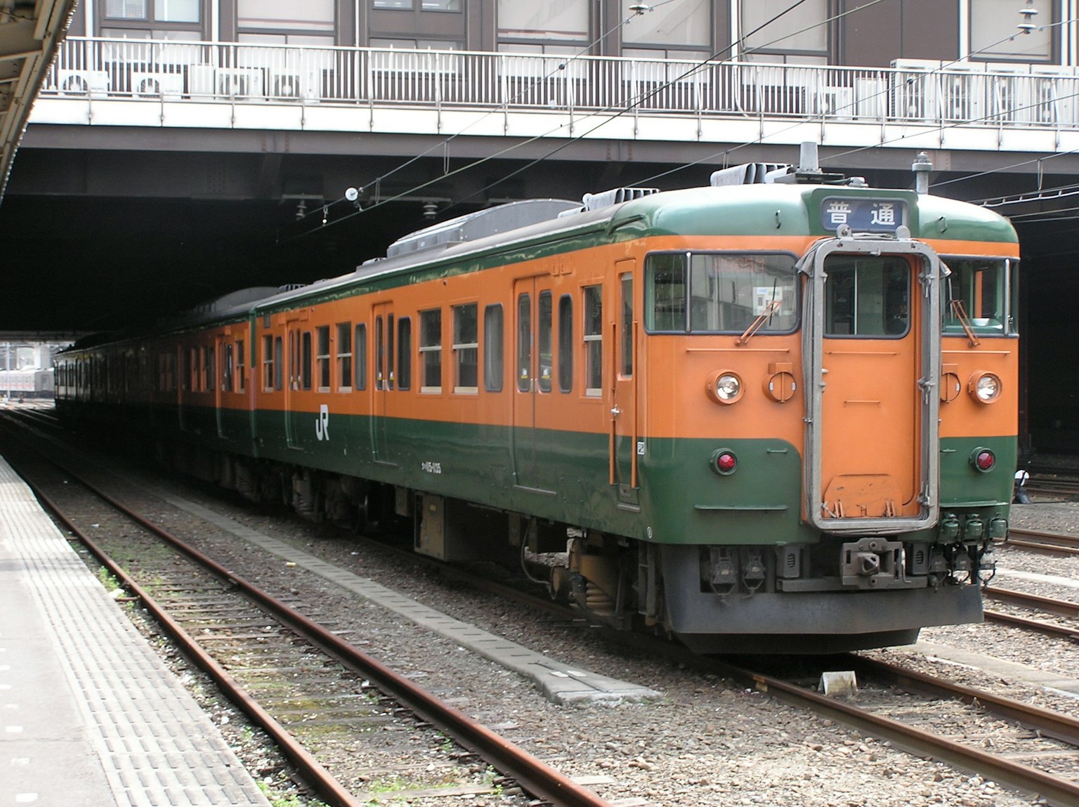 Kereta Jepang berwarna oranye dan hijau berhenti di stasiun