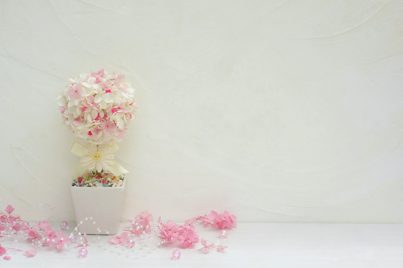 Potted arrangement of pink and white flowers against a white background