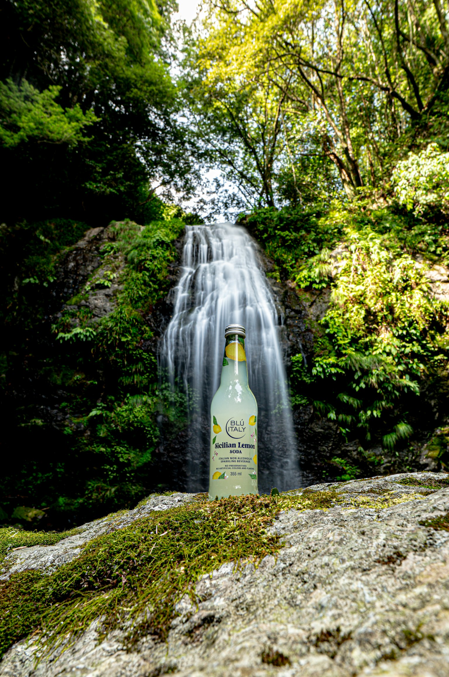 Une bouteille transparente placée devant une cascade entourée de verdure luxuriante