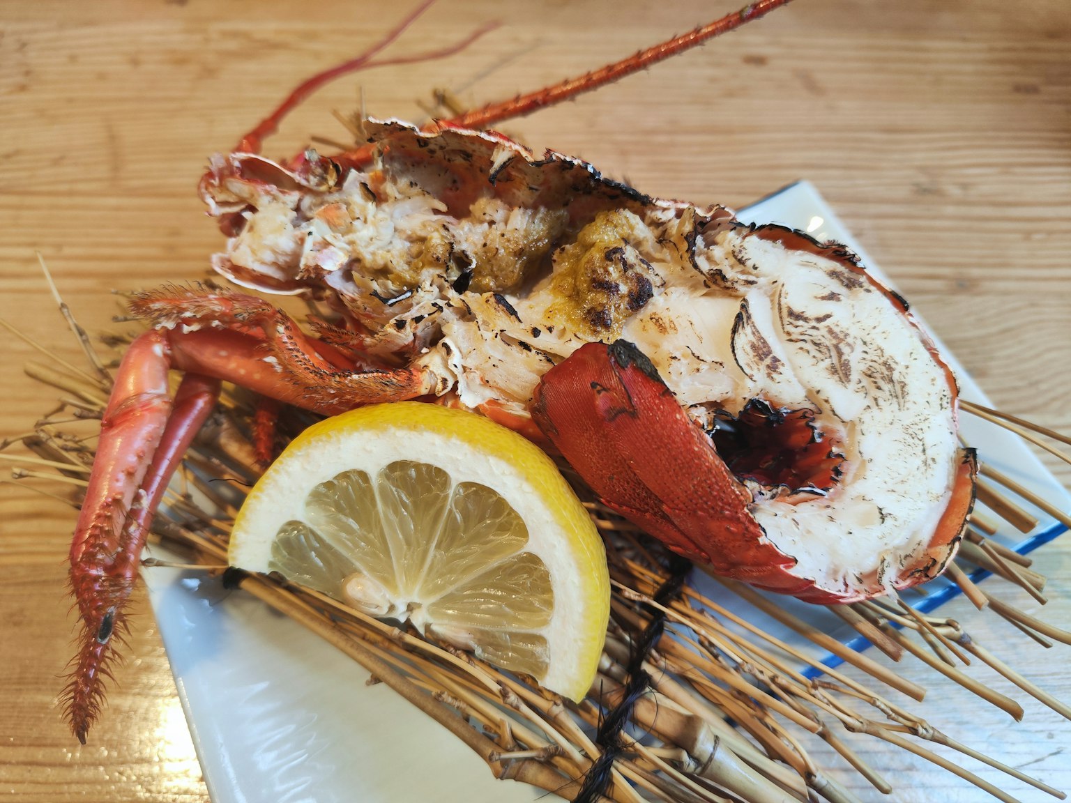 Half a fresh lobster served with a slice of lemon on a plate
