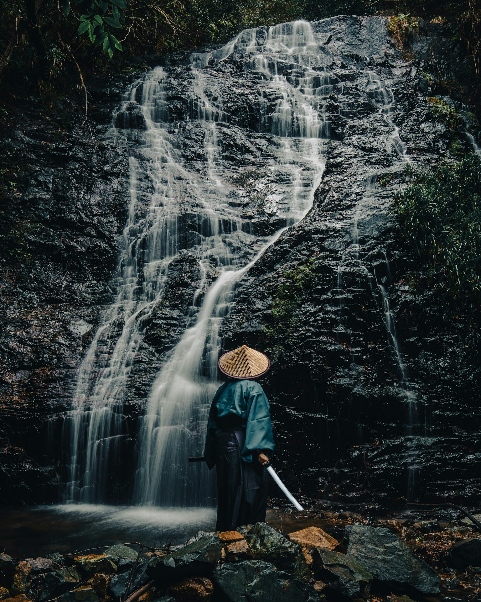 Une figure ressemblant à un samouraï tenant une épée devant une cascade