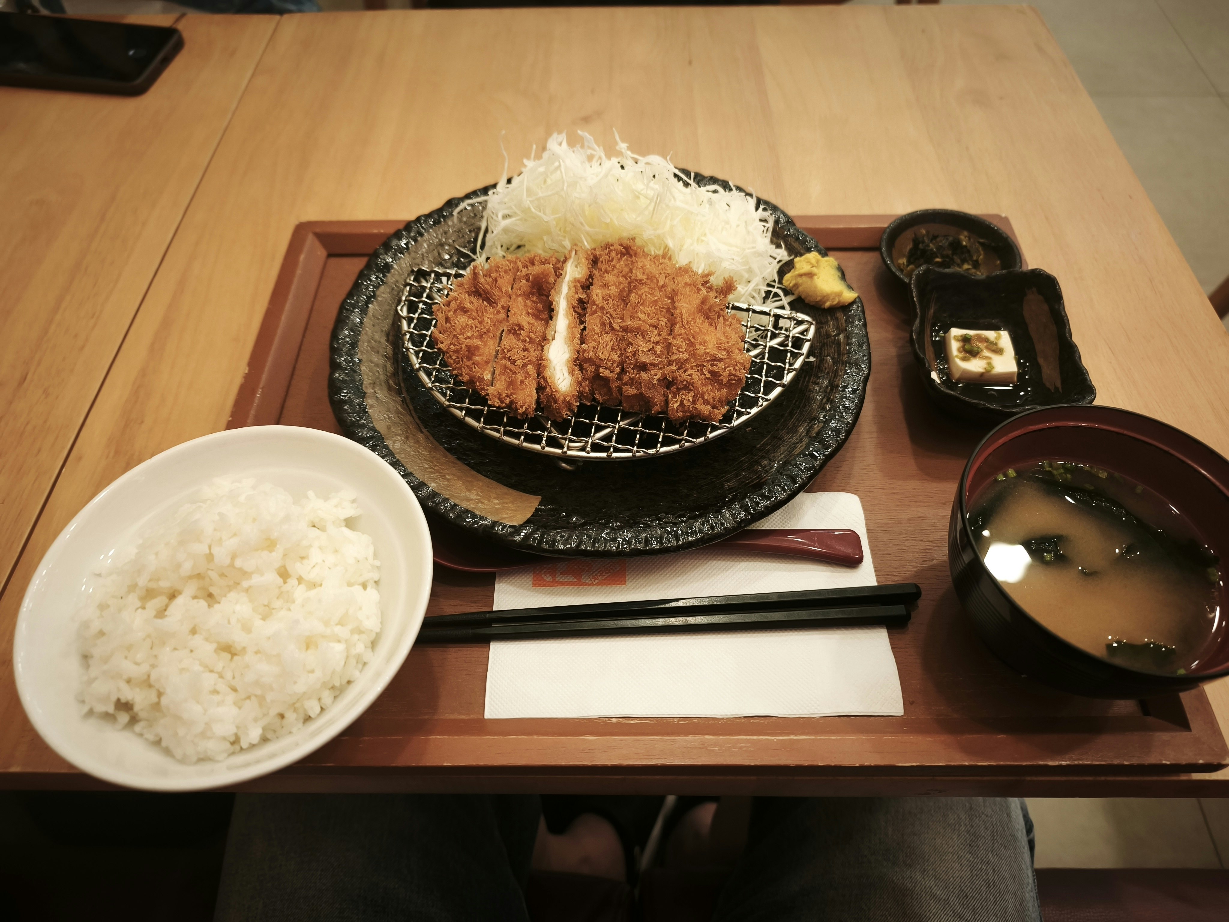 木目のテーブルに並ぶ和食の定食（ご飯・味噌汁・揚げ物）