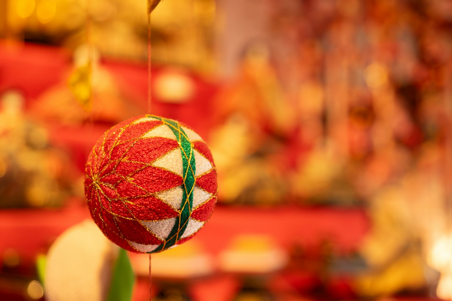 Une boule décorative rouge et blanche suspendue devant un fond rouge flou
