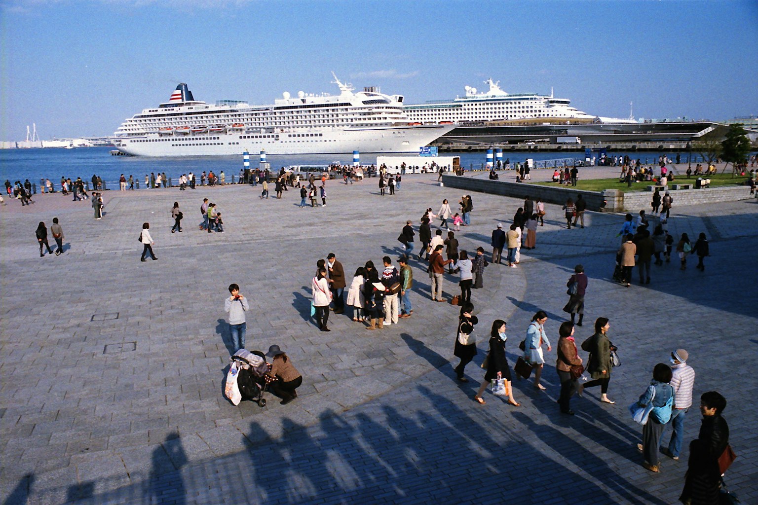 Gran crucero atracado junto al mar con personas disfrutando de la plaza