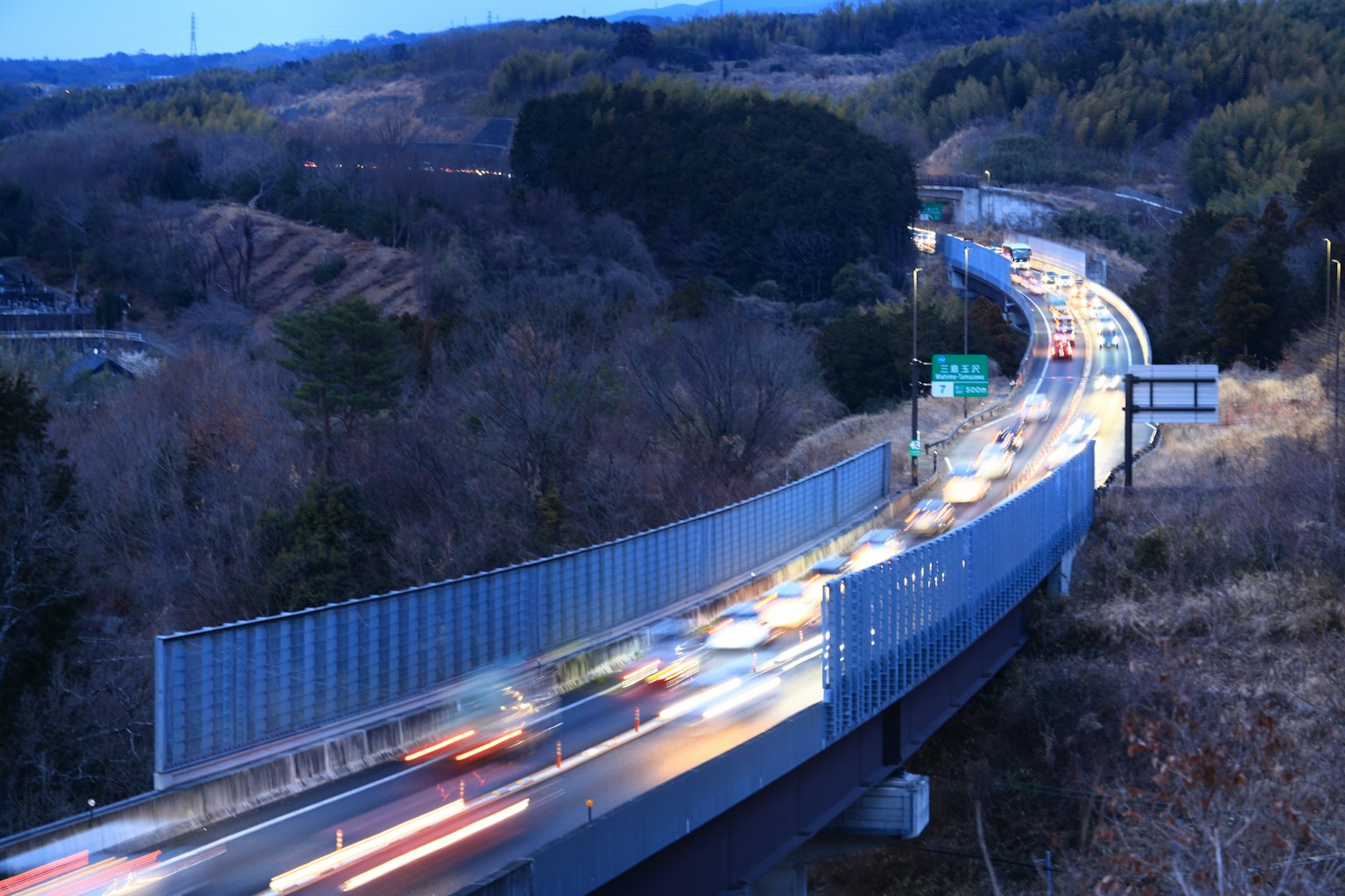 Vista notturna di un'autostrada con luci di auto e paesaggio montano