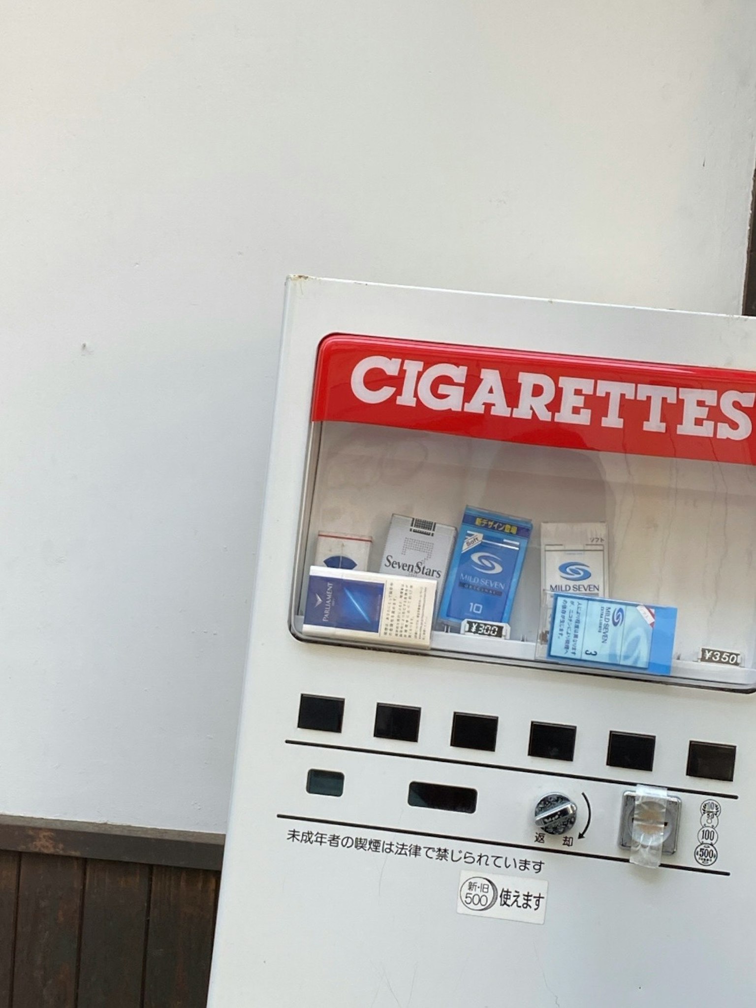 Un distributore automatico di sigarette di fronte a un muro bianco