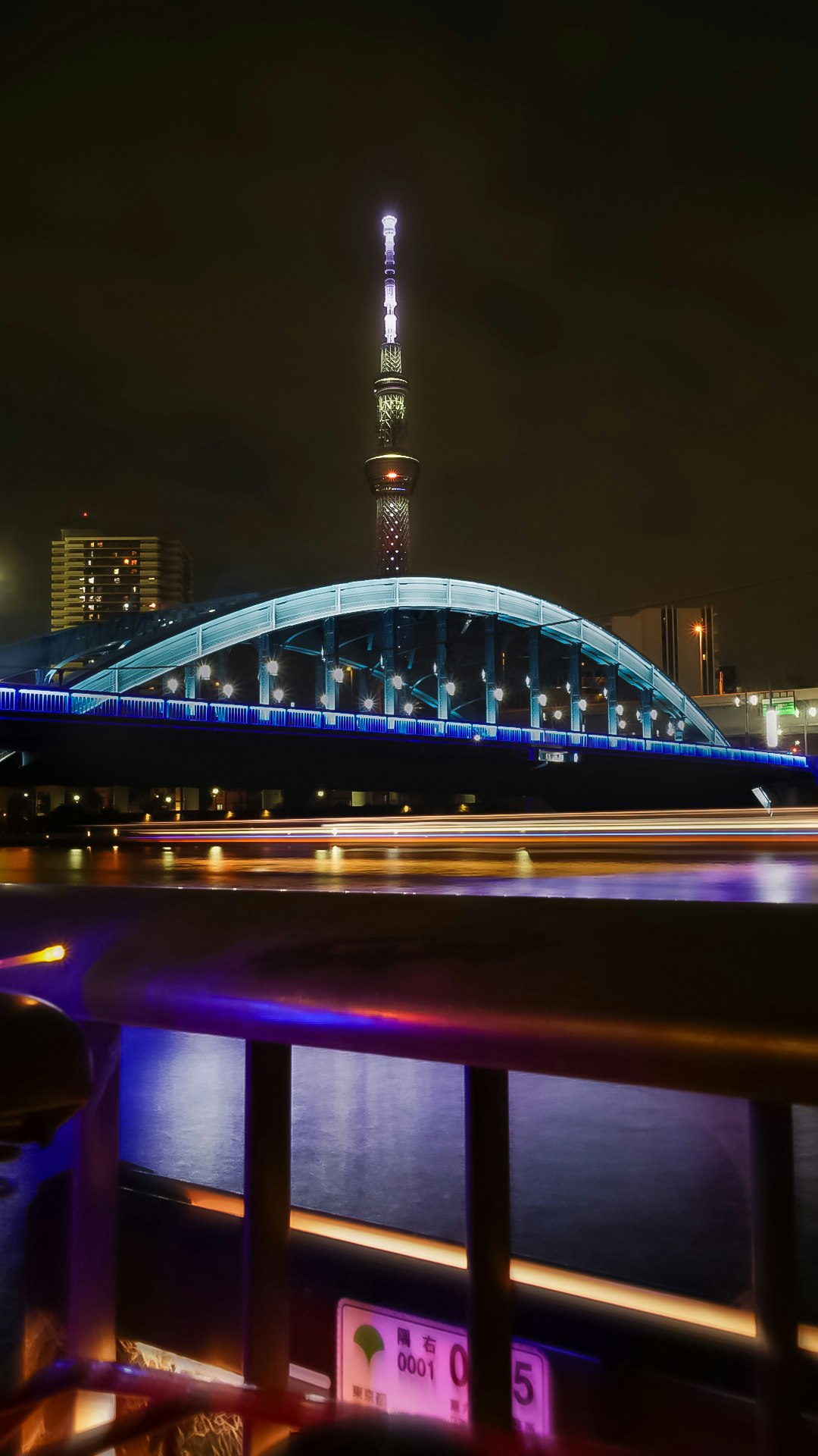 夜の川沿いにライトアップされた橋とタワーの眺め