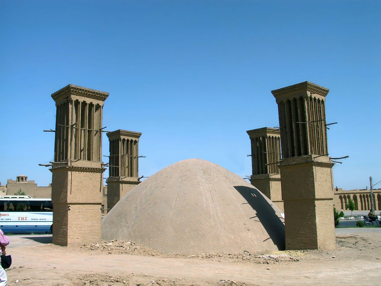 Ein Sandhügel umgeben von vier Windfängern in einer trockenen Landschaft