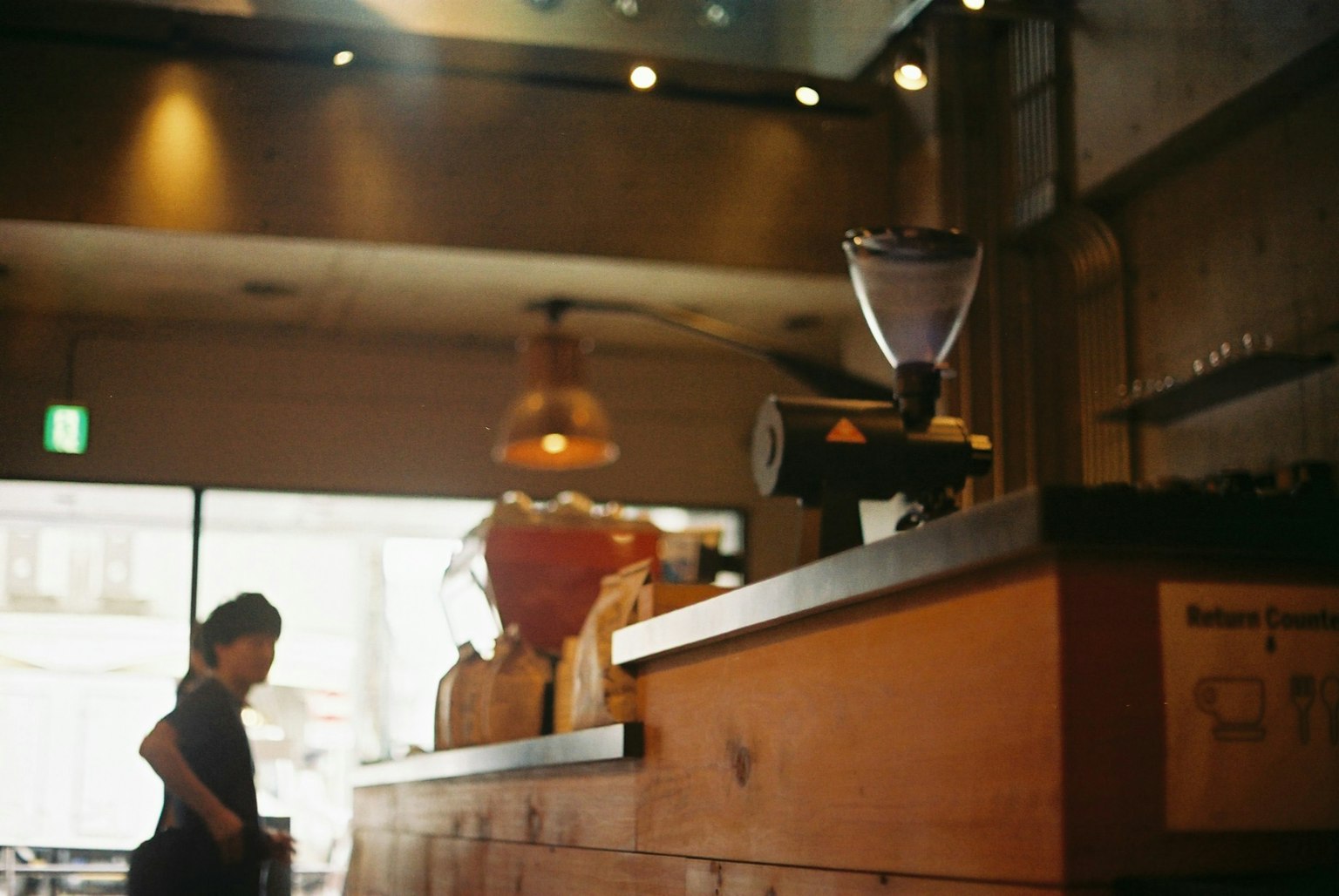 Interior of a café with a barista at work warm lighting wooden counter and coffee grinder visible