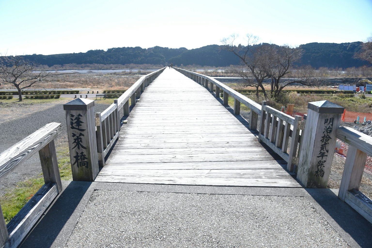 Holzbrücke, die sich in eine Landschaft mit natürlicher Szenerie im Hintergrund erstreckt