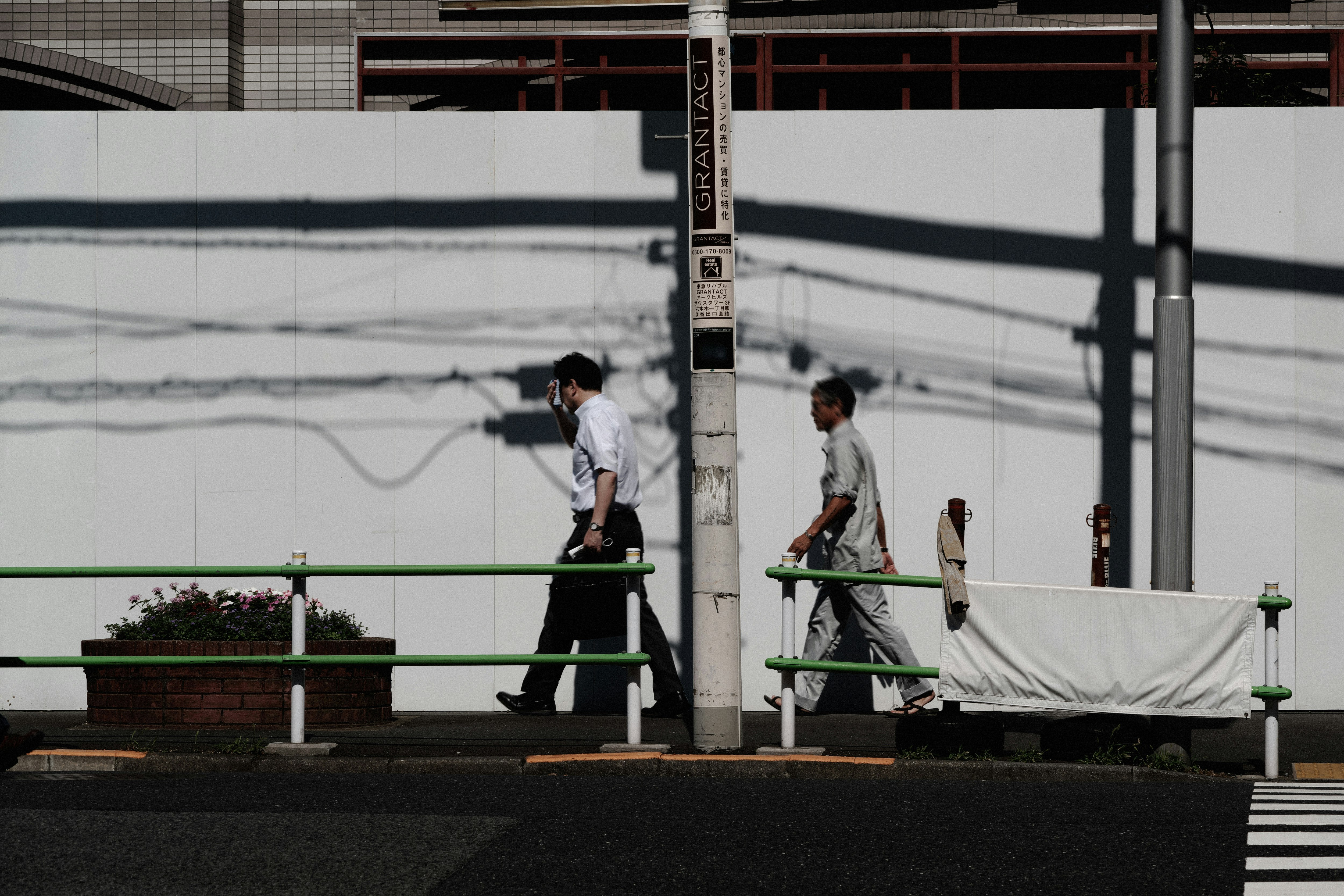路地の壁沿いを歩く人と自転車のある街角