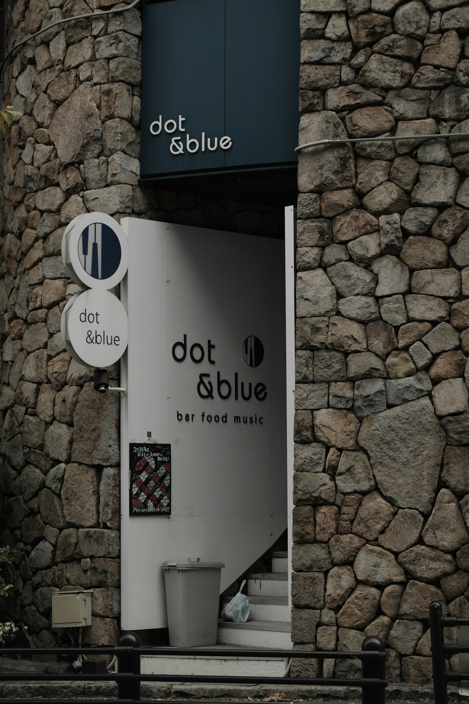 ทางเข้าของ dot & blue กับพื้นหลังเป็นผนังหิน