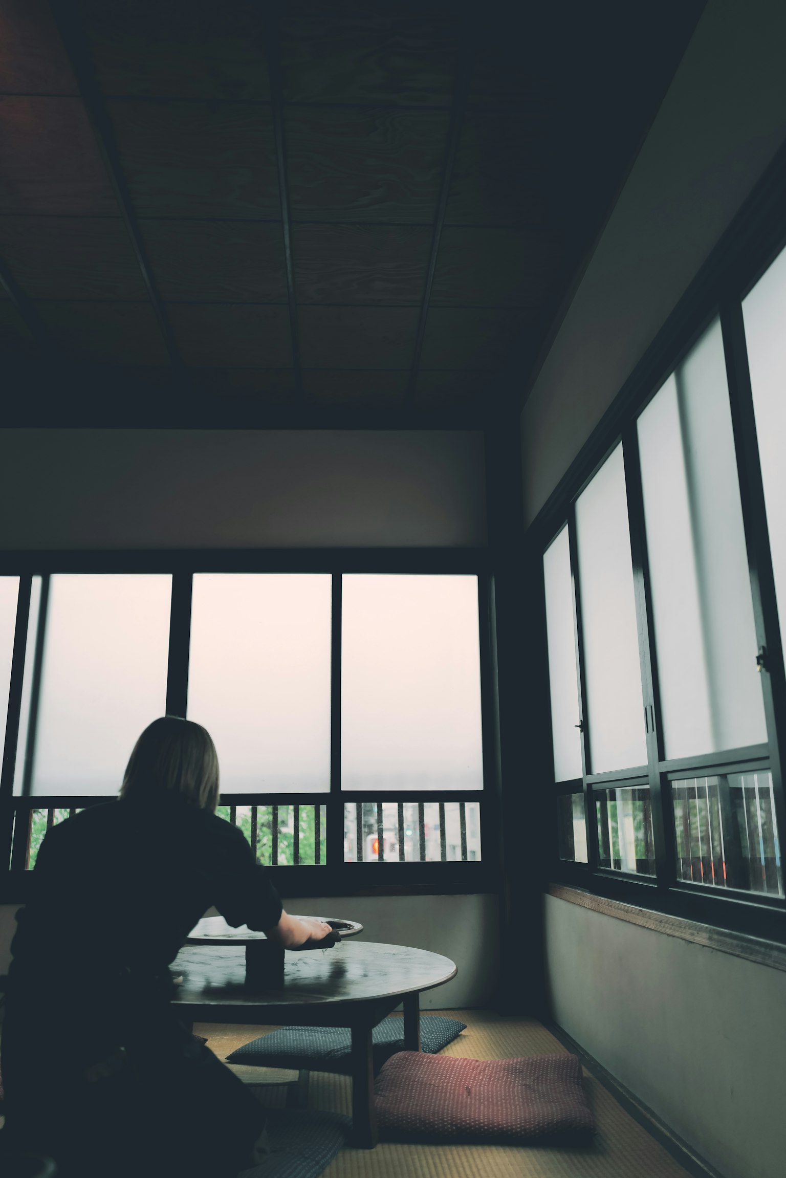 Người ngồi bên cửa sổ trong một căn phòng yên tĩnh quay lưng và đặt tay lên bàn