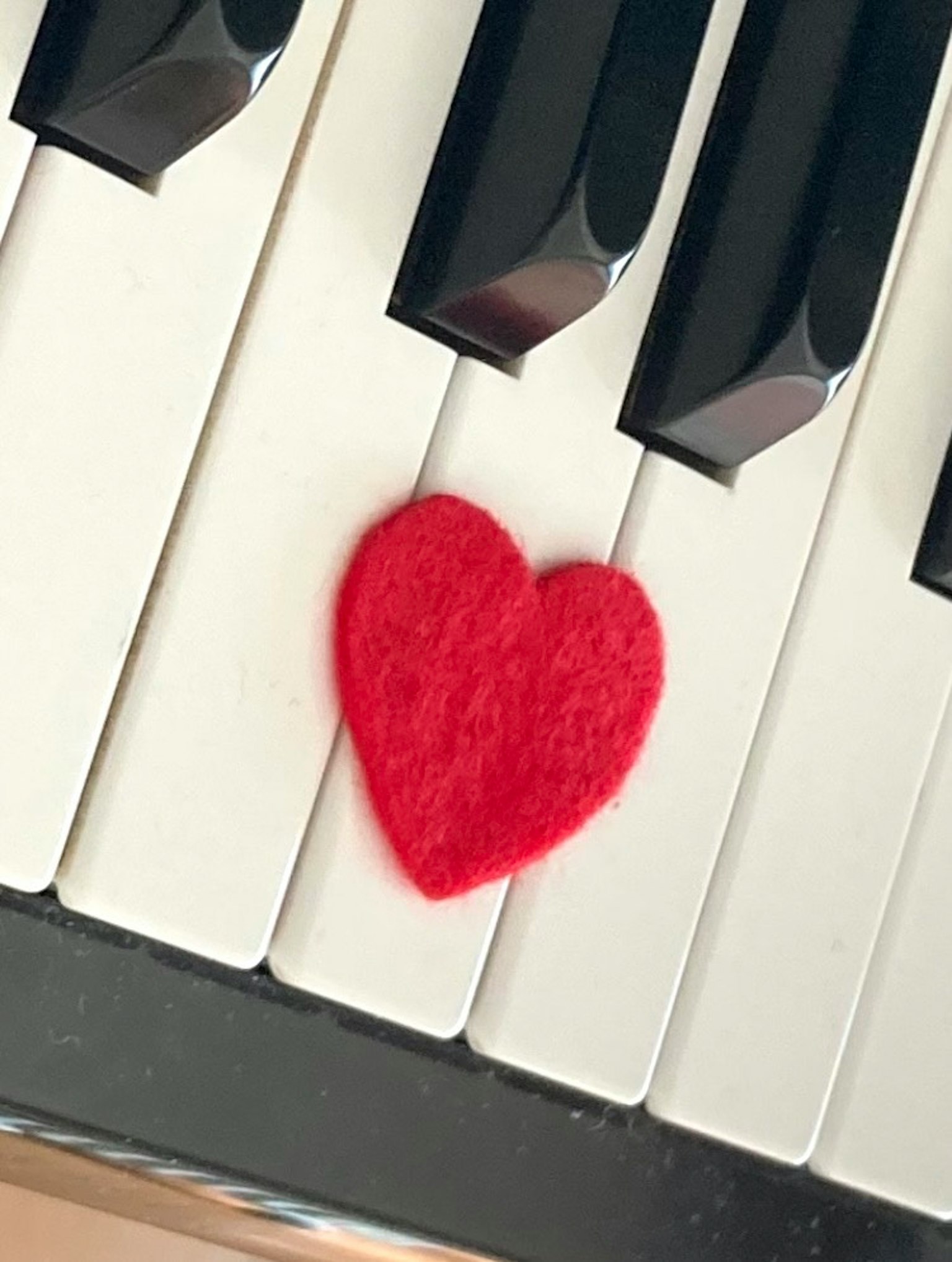 Cuore rosso in feltro posizionato sui tasti del pianoforte