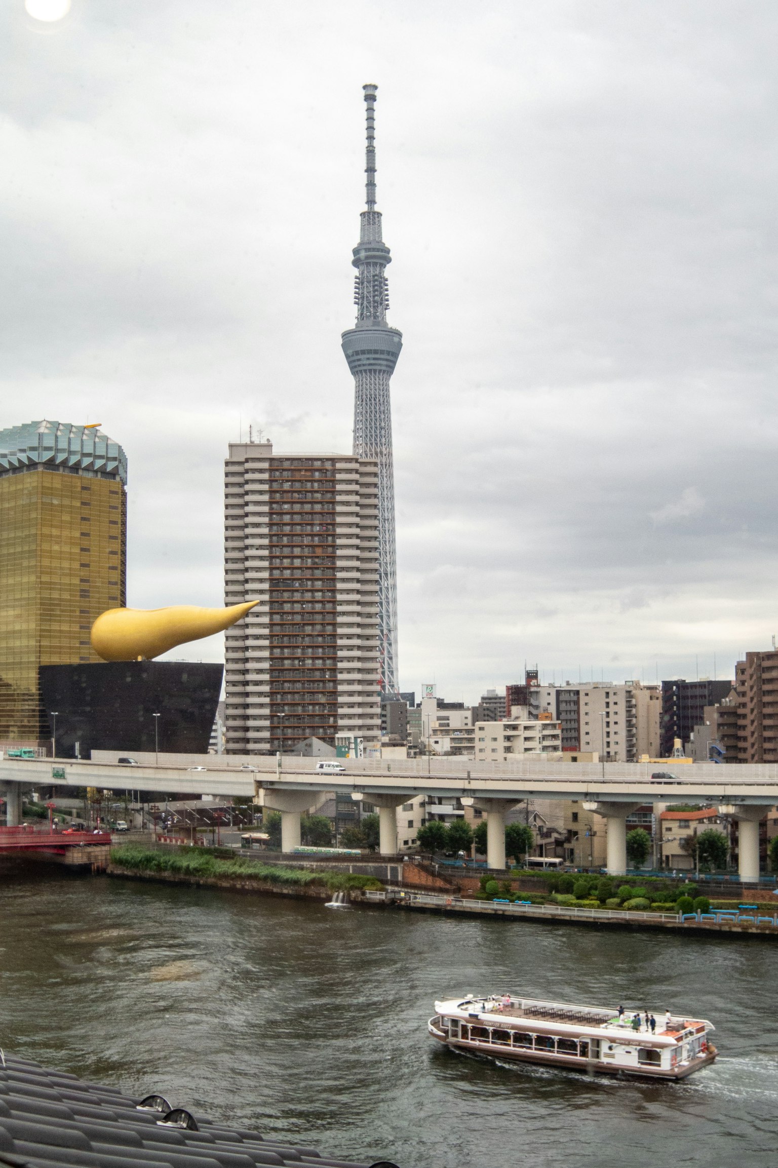 Vista della Tokyo Skytree e del fiume Sumida con edifici vicini e una barca