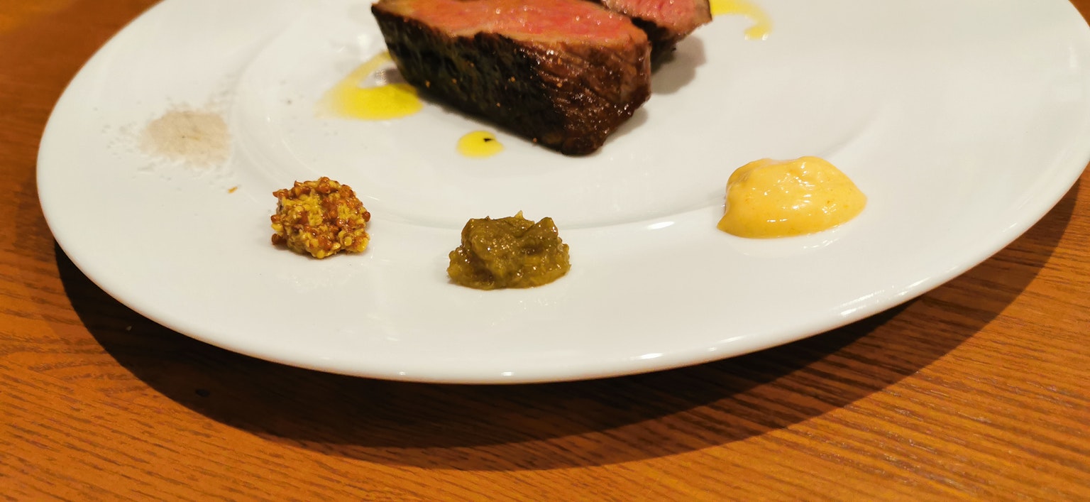 Teller mit einem Stück Fleisch und drei Arten von Saucen