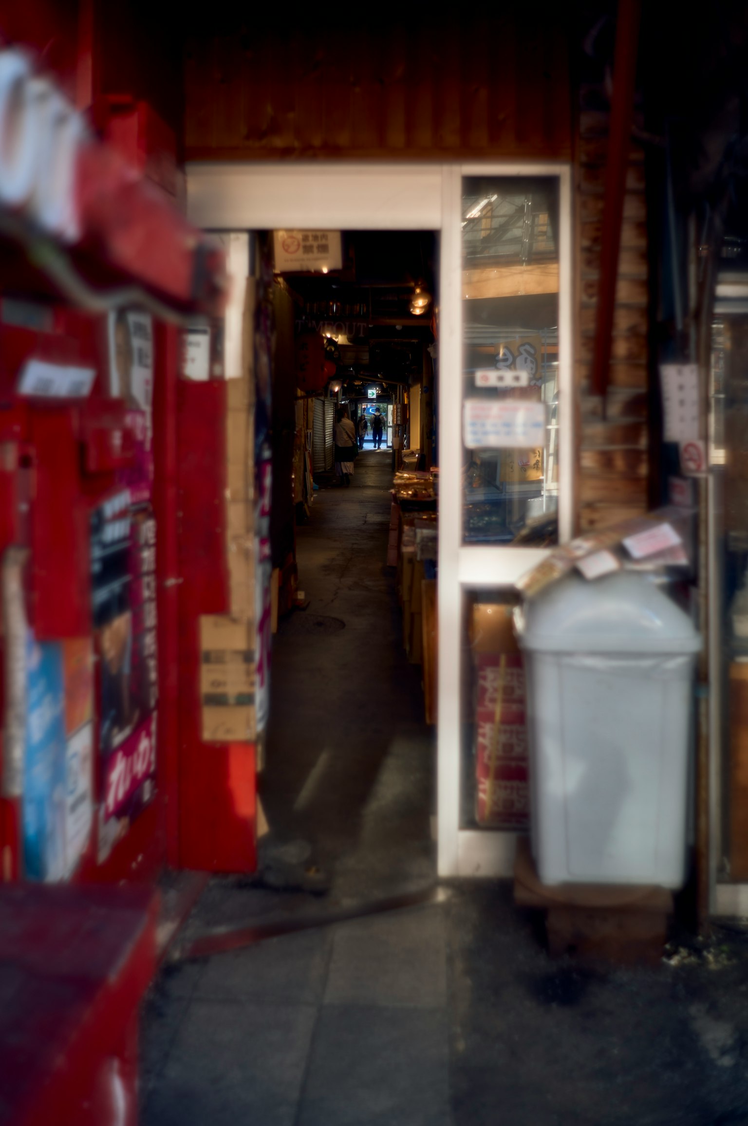Entrée d'un passage étroit avec une porte blanche et des murs rouges de magasins