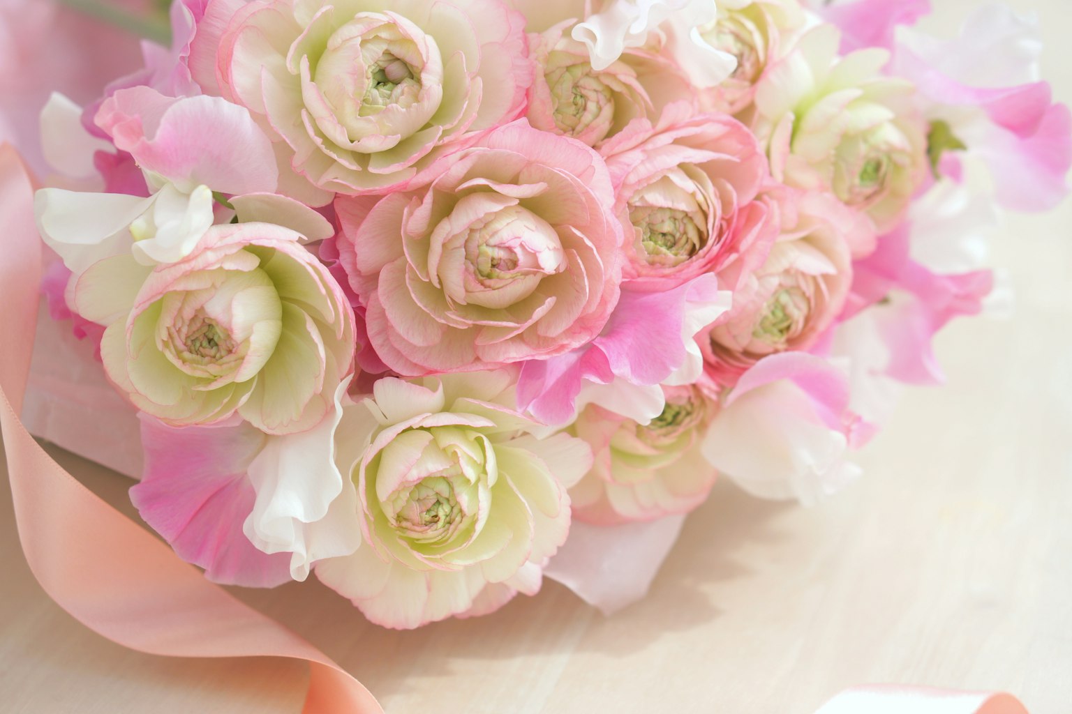 一束柔和的粉色和白色花朵,包括 ranunculus 和兰花