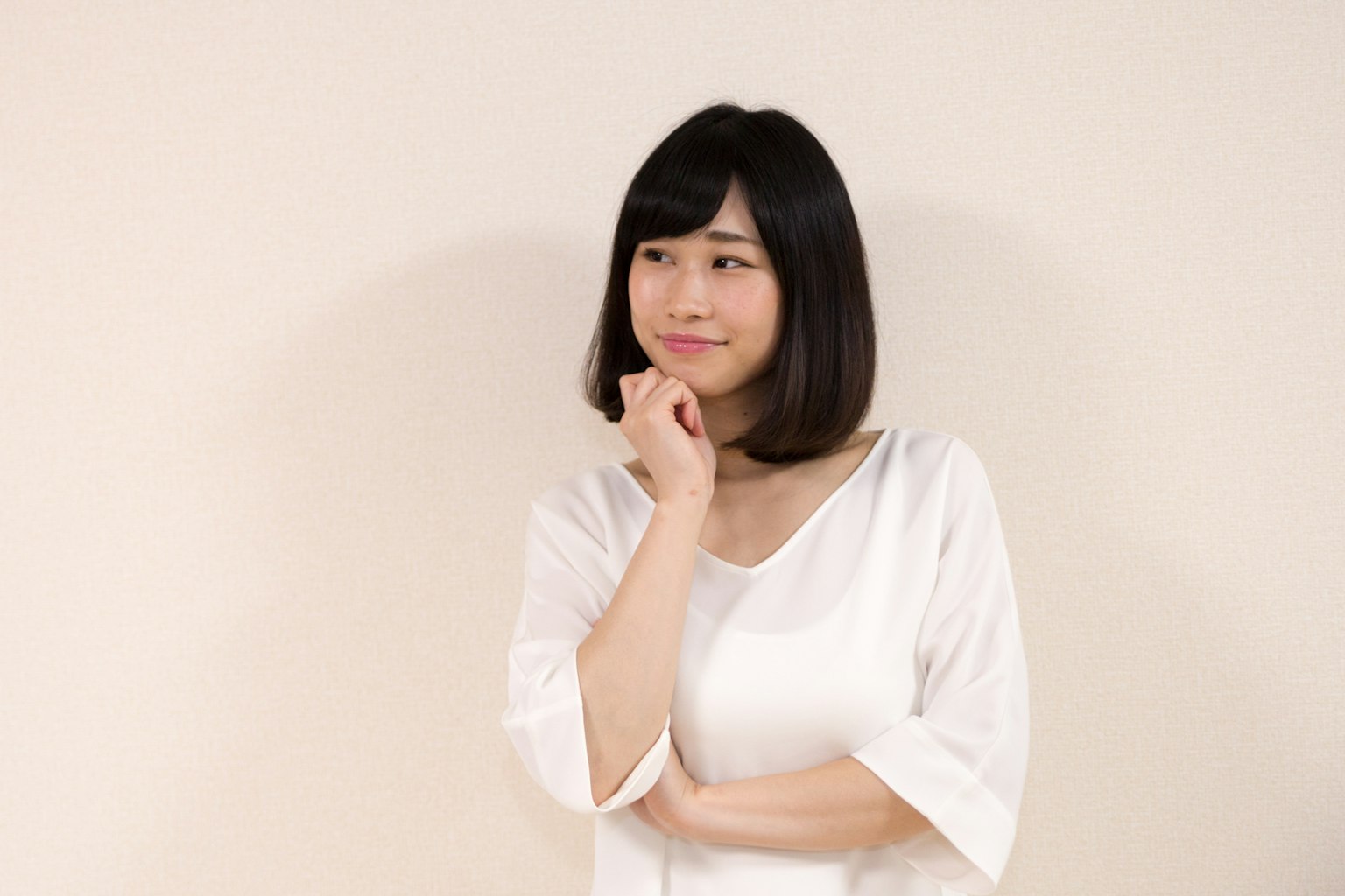 Woman in a white top with a thoughtful expression