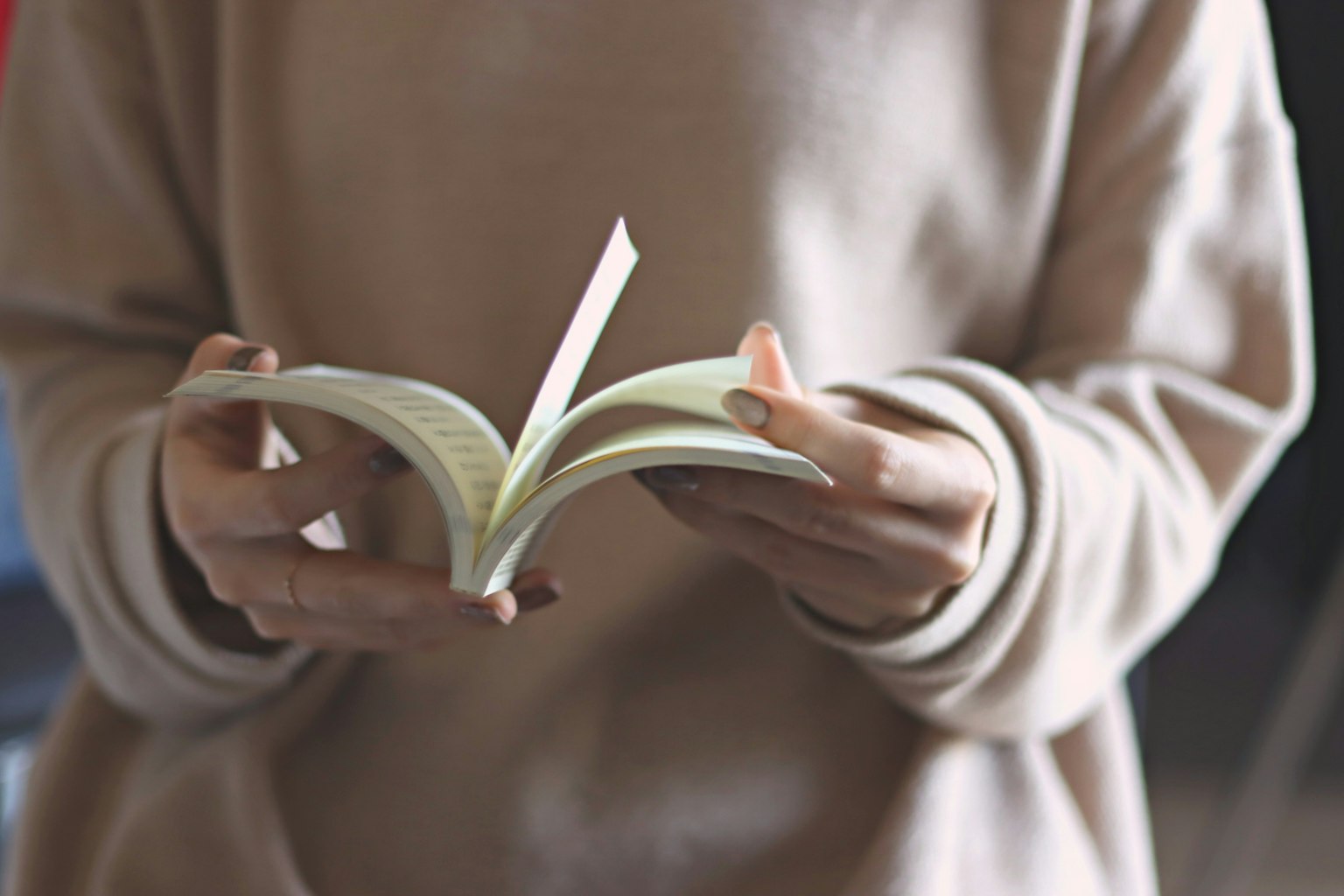 Primer plano de una mujer sosteniendo un libro con un suéter suave