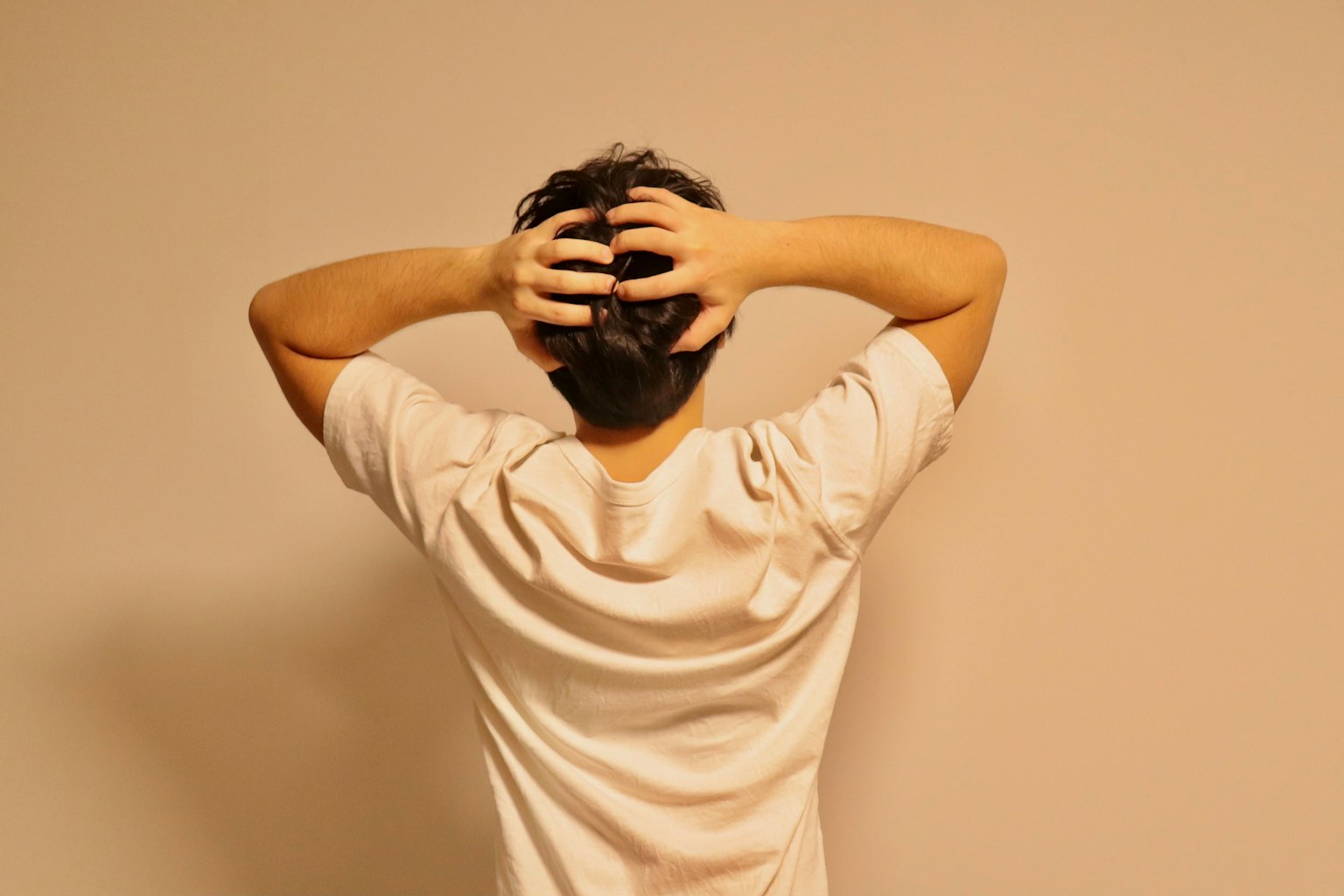 Un homme en chemise blanche se tenant la tête avec les deux mains