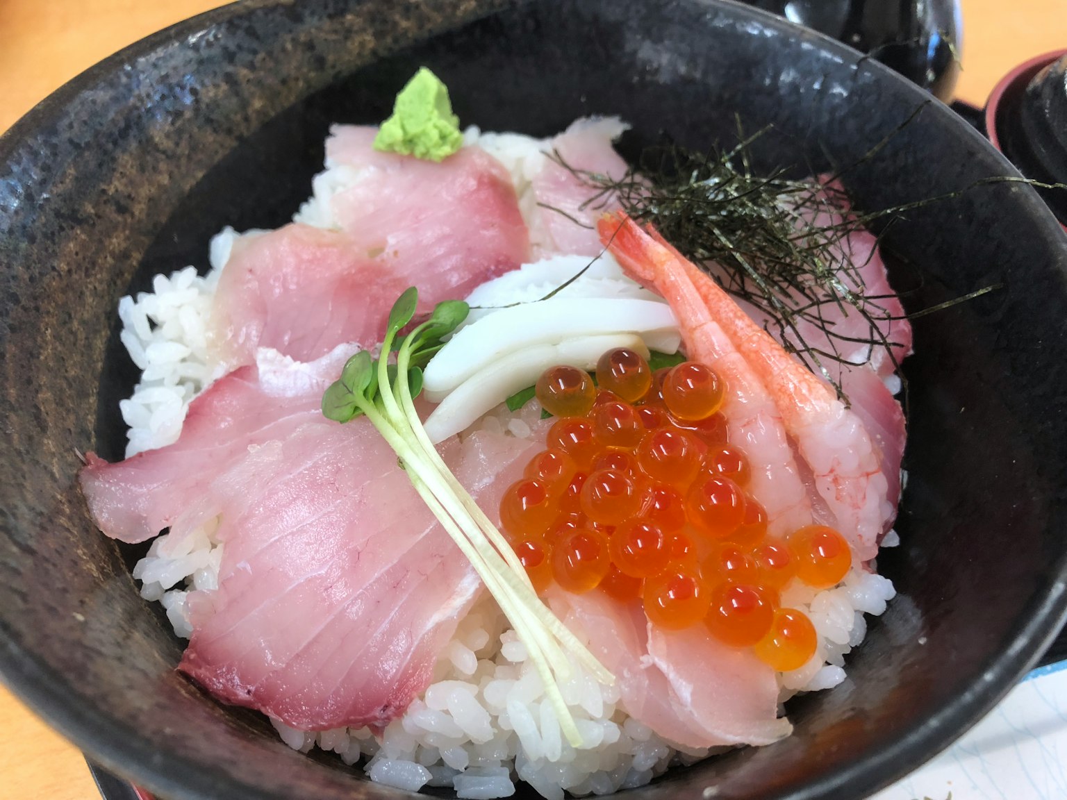 Tazón de arroz cubierto con sashimi fresco y huevas de salmón