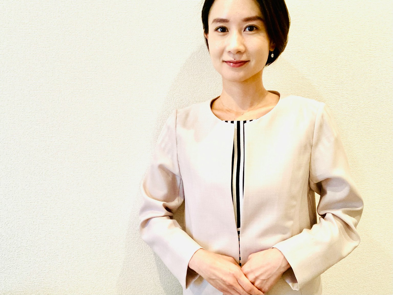 一位微笑的女性穿着简单设计的浅粉色夹克