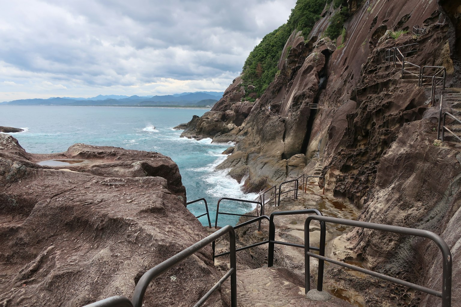Vue panoramique de la côte rocheuse avec des escaliers et une rampe