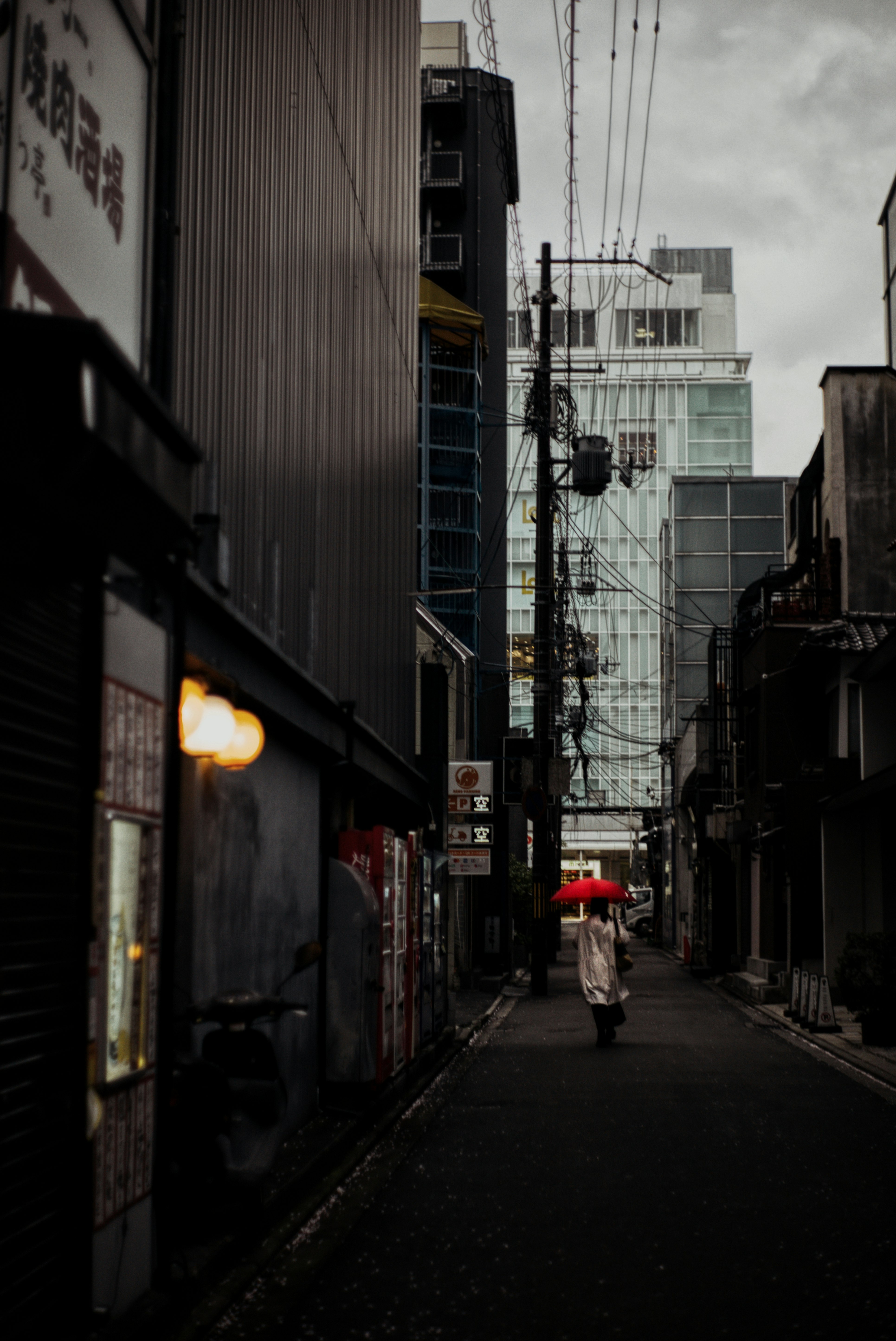 雨の路地を歩く人と傘のある商店街の軒先