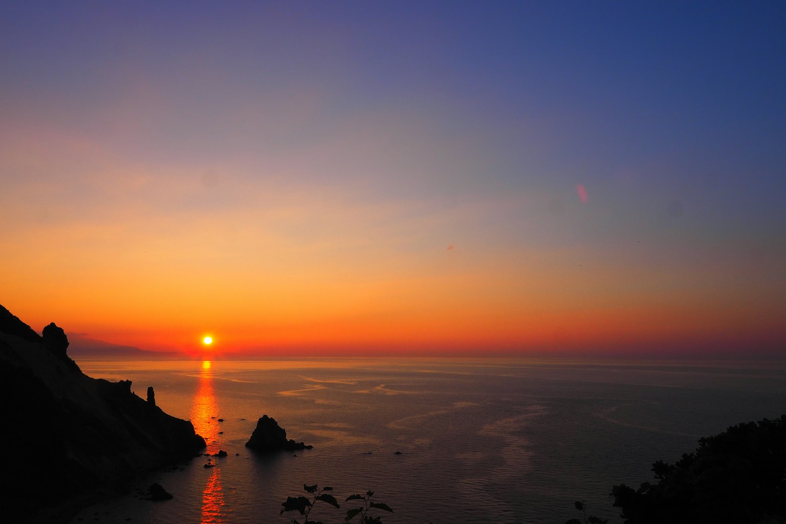 Beautiful sunset over the ocean with rock silhouettes