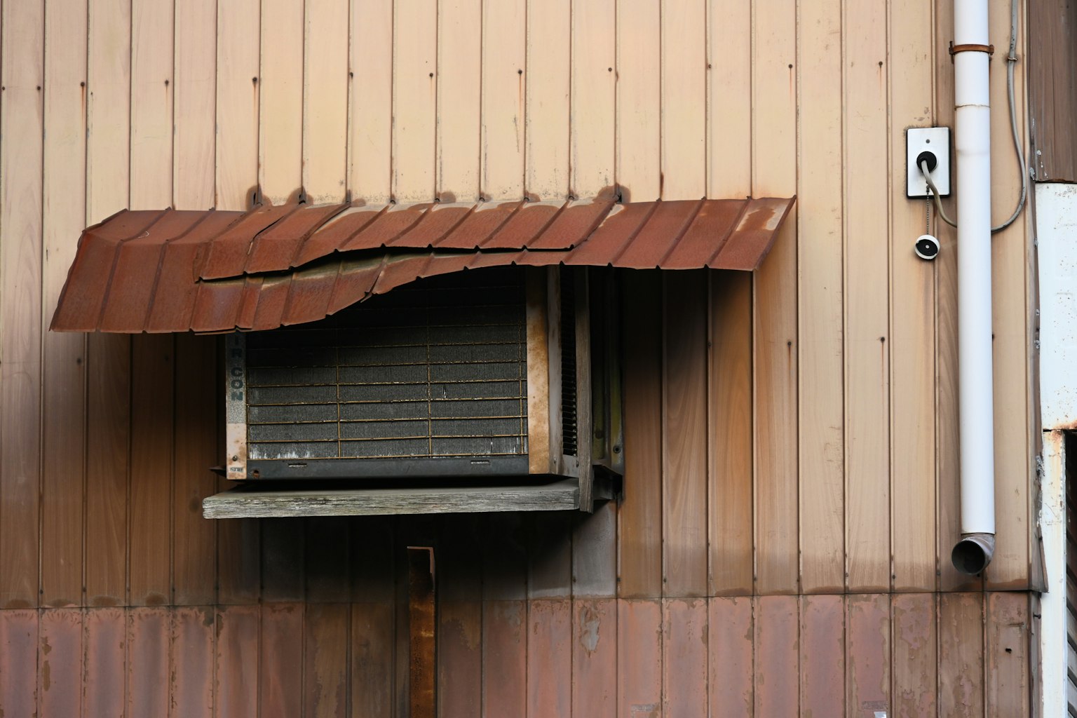 Ancien climatiseur avec auvent rouillé sur le mur
