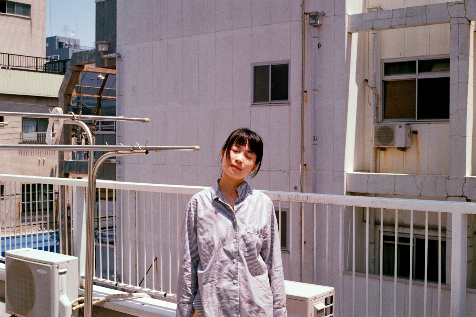 一位女性站在屋頂上，背景是城市建築的肖像