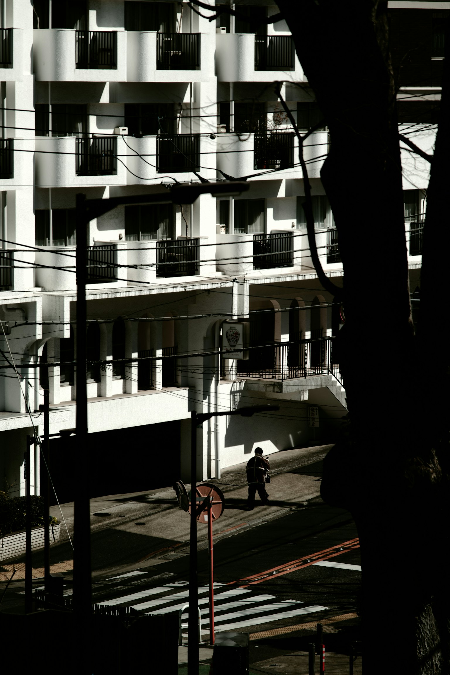 Una persona che cammina su una strada con un edificio bianco sullo sfondo