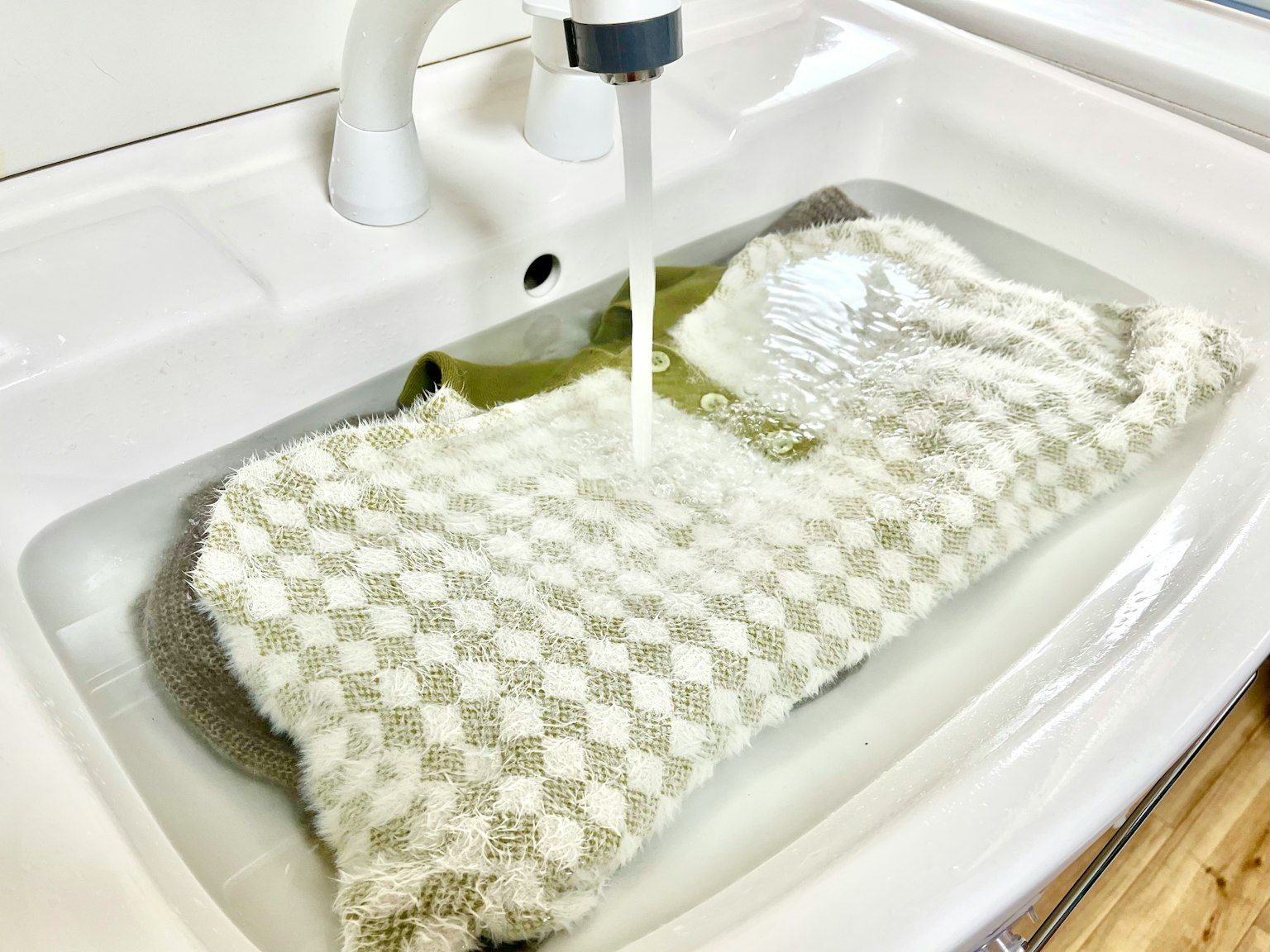 Asciugamano a scacchi bianco e verde in ammollo in acqua in un lavandino