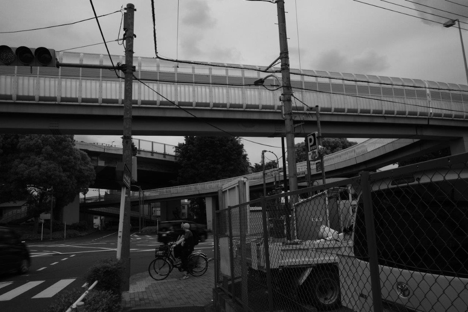 Schwarz-weiß städtische Szene mit einer erhöhten Brücke und einem Radfahrer