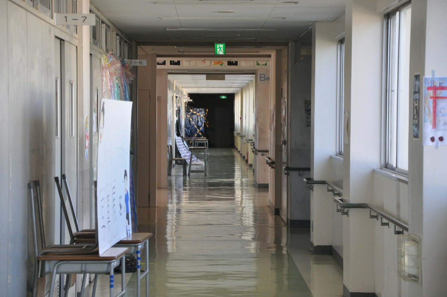 Un largo corredor de hospital con luz tenue sillas y un cartel a lo largo de las paredes
