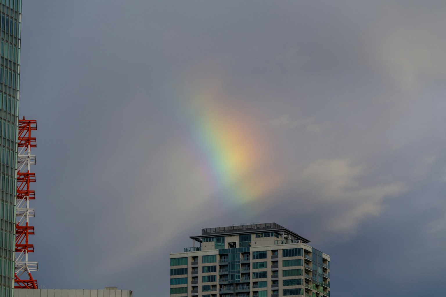 Arcobaleno che appare sopra un grattacielo sotto cieli nuvolosi