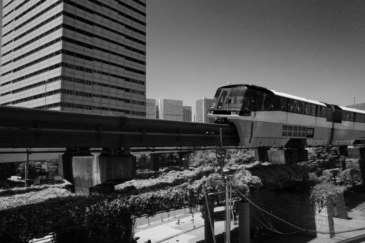kereta melintas di bawah struktur layang dengan gedung perkantoran kota
