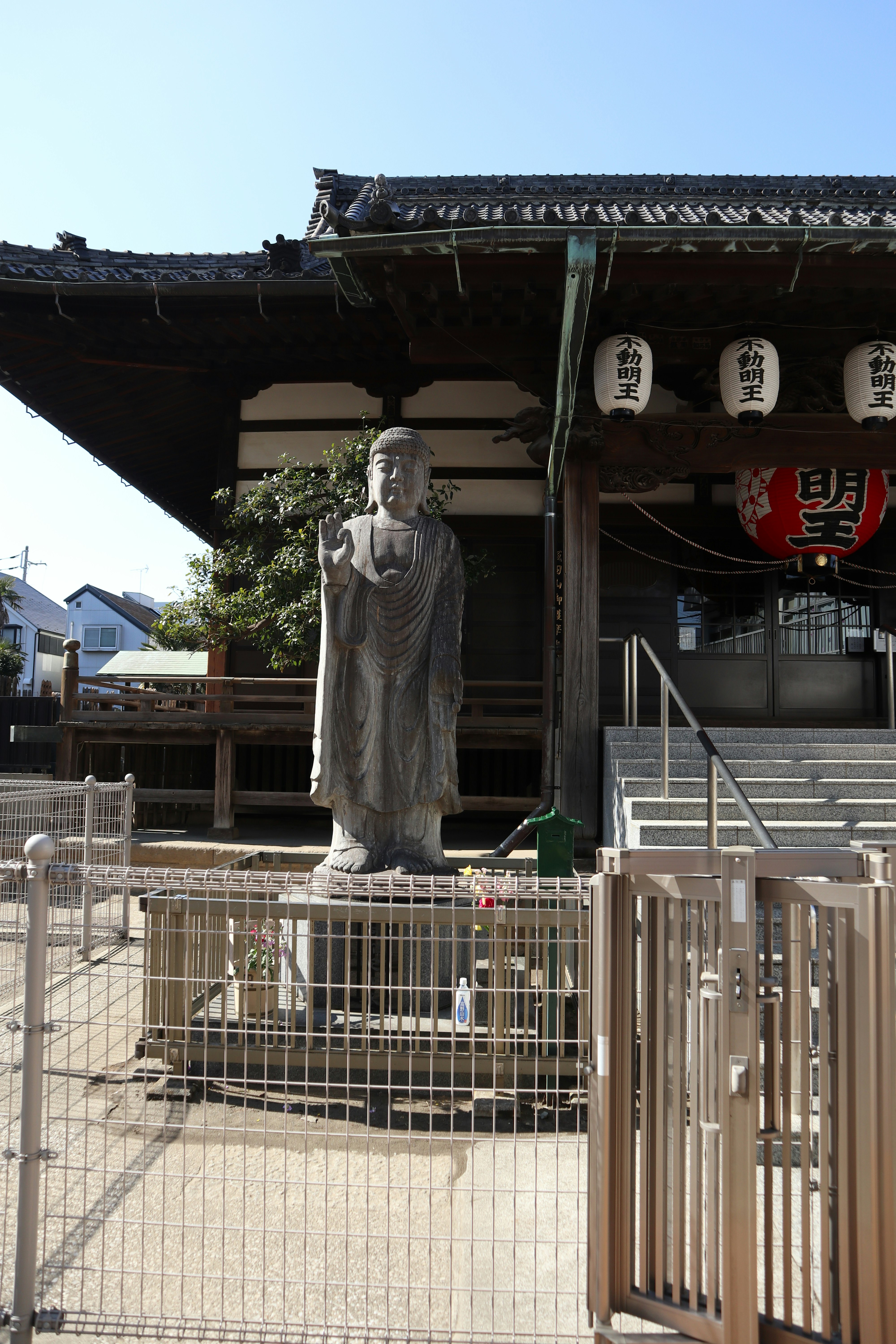 神社の境内で囲いの中に立つ銅像と看板