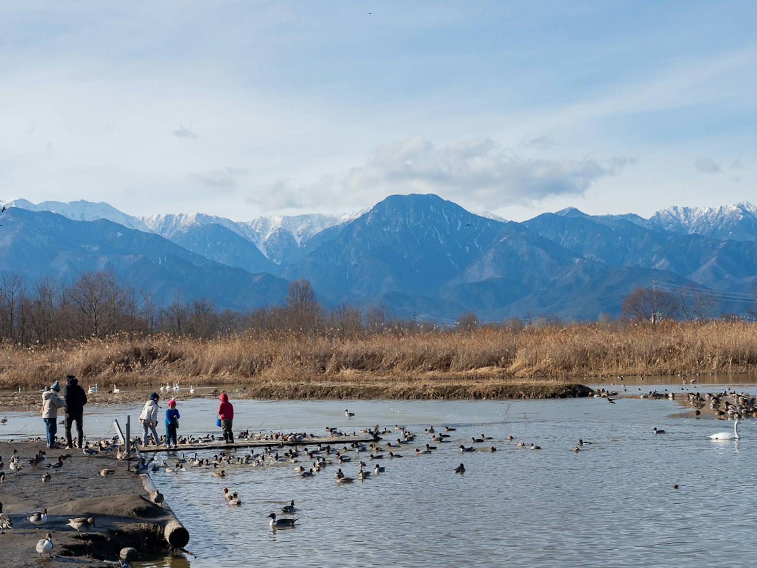 Eine Familie, die am Wasser Spaß hat, mit schneebedeckten Bergen im Hintergrund