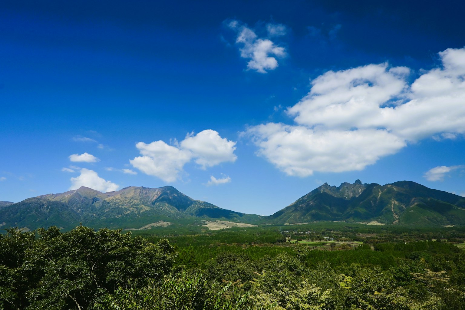 Scenic view of mountains under a blue sky with fluffy clouds